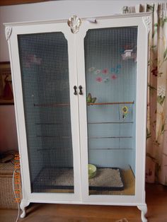 a white cabinet with two doors and a cat bed in front of it on top of a hard wood floor