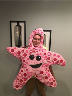 a man standing in front of a wall with a pink star shaped pillow on it