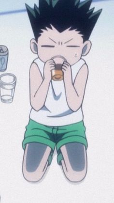 a young boy sitting on the ground with his eyes closed and drinking from a cup