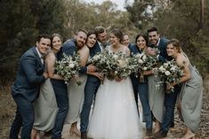 a group of people standing next to each other in front of some trees and bushes