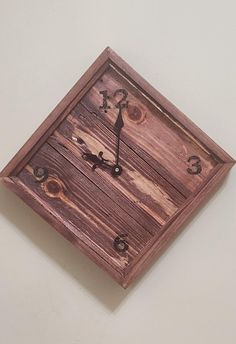 a square wooden clock mounted to the side of a wall