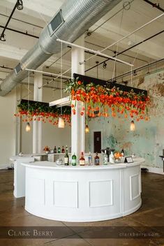 the bar is decorated with orange flowers and greenery hanging from it's ceiling