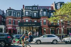 a woman riding a bike down a street next to parked cars