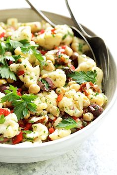 a white bowl filled with cauliflower salad and garnished with parsley