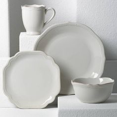 white dishes and cups are stacked on top of each other, with one empty bowl in the middle