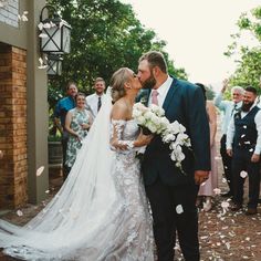 a bride and groom kiss as they walk down the aisle after their wedding ceremony with confetti thrown in the air