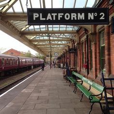 a train station with benches and people walking on the platform