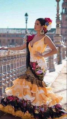 a woman in a yellow dress leaning on a fence