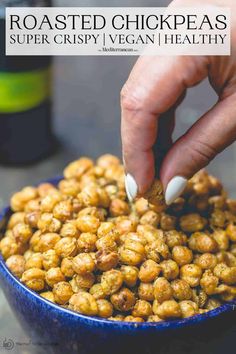 a person dipping peanuts into a blue bowl with their fingers on the top of it