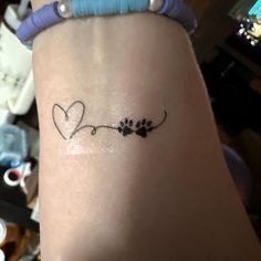 a woman's arm with a small heart and paw prints on it, in the shape of a flower