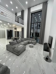 a large living room with white marble floors and gray couches in front of a flat screen tv