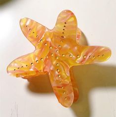 an orange and yellow glass starfish on a white surface