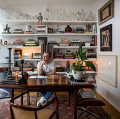 a man sitting at a table in front of a bookshelf filled with books