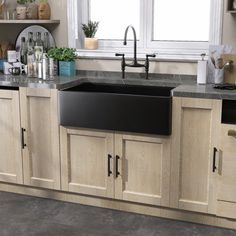 a kitchen with wooden cabinets and black granite counter tops is pictured in this image, there are plants on the window sill