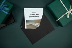 two wrapped presents sitting next to each other on top of a green surface with a card in the middle