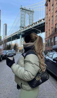 a woman is walking down the street with her hand in her pocket and looking at her cell phone