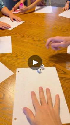 a group of children sitting around a wooden table playing with dices and paper on it