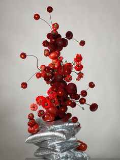 a silver vase filled with red flowers on top of a table