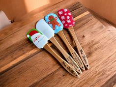 four wooden spatulas with christmas decorations on them sitting on top of a table