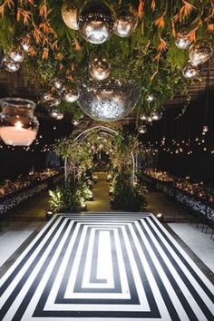 an indoor wedding venue with black and white striped flooring, chandeliers hanging from the ceiling