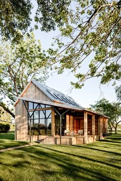 a small wooden cabin in the middle of a field with grass and trees around it