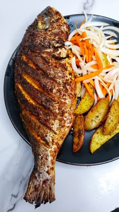 a plate with fish, potatoes and carrots sitting on top of it's side