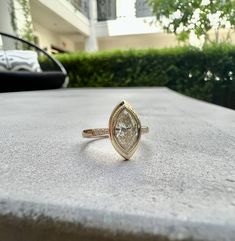 a diamond ring sitting on top of a stone table next to some bushes and trees