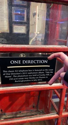 there is a sign that says one direction on the side of a red phone booth