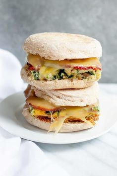 three sandwiches stacked on top of each other on a white plate with cheese and broccoli