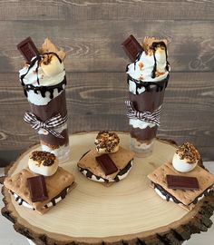 three desserts are arranged on top of a tree stump with chocolate and marshmallows