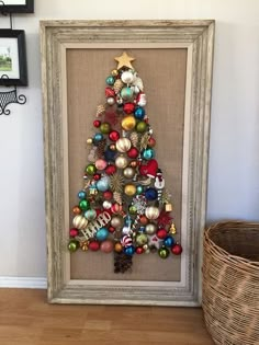 a christmas tree made out of ornaments in a frame on the floor next to a basket