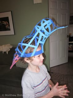 a young boy wearing a paper hat made to look like a bird with blue strips on it