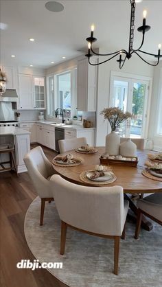 a dining room table and chairs in front of an open kitchen area with white cabinets