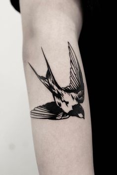 a black and white bird tattoo on the arm