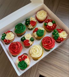 twelve cupcakes in a box decorated with red, green and white frosting