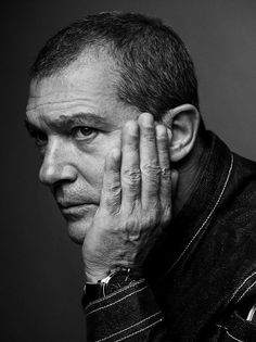 a black and white photo of a man holding his hand to his face with both hands