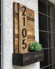 a house number sign mounted to the side of a building next to a planter