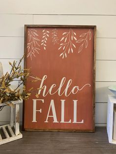 a wooden sign that says hello fall next to a vase with some flowers in it