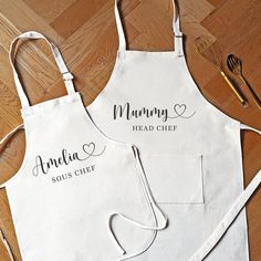 two personalized aprons are sitting on the floor with utensils next to them