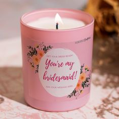 a pink candle that is sitting on a doily with the words you're my bridesmaid printed on it