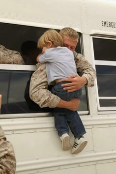 a man in uniform holding a small child up to his face as they look out the window