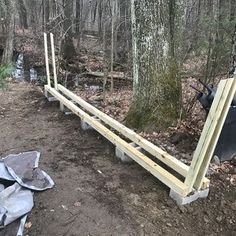 a wooden bench sitting in the woods next to a pile of garbage and trash bags