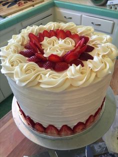 a cake with white frosting and strawberries on top is sitting on a table