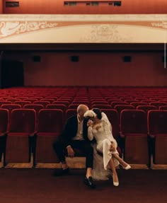 a bride and groom sitting in an empty theater