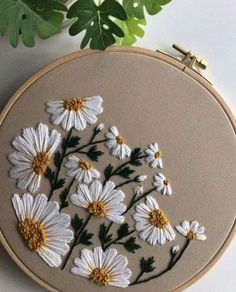 white daisies are embroidered onto an embroidery hoop