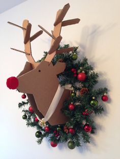 a cardboard reindeer head hanging on the wall with christmas decorations around it and a wreath