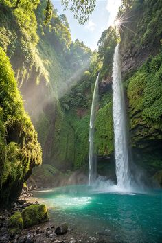 a large waterfall in the middle of a forest with blue water and green plants on both sides