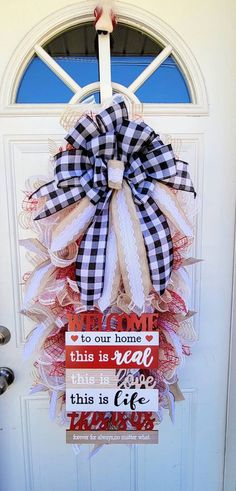 a welcome sign hanging on the front door to someone's house with a large bow