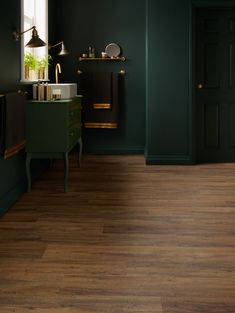 a room with green walls and wooden floors, including a sink in the middle of the room