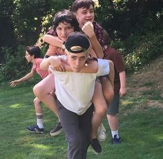 a group of young people standing on top of each other in the grass with their arms around one another